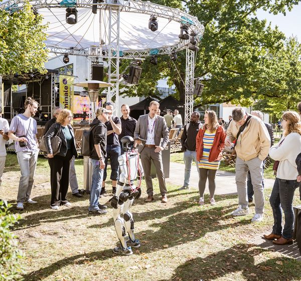 Gäste umringen einen humanoiden Roboter