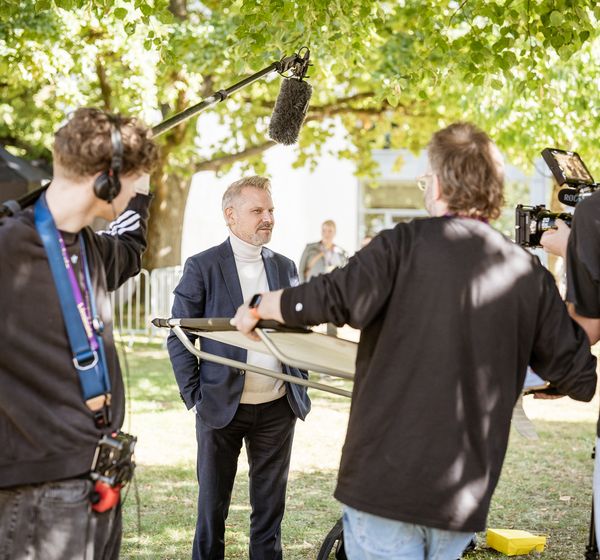 Interview vor der Kamera unter Bäumen