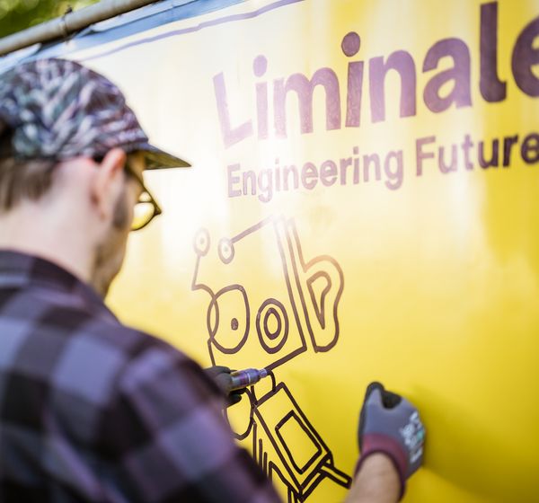 Künstler zeichnet ein Motiv auf das Liminale-Banner